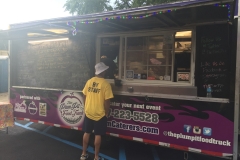 Staff member standing in front of The Plum Pit Food Truck.